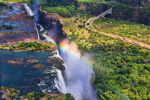 View from above of waterfall cascading into a gorge, creating lots of spray and a rainbow.