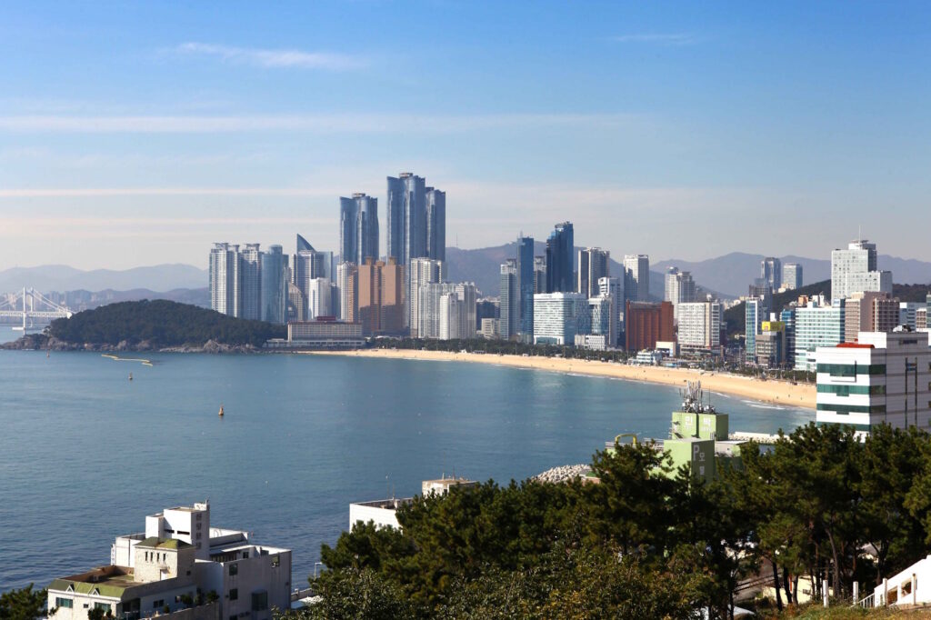 Long distance shot of the city of Busan, South Korea, fronted by the yellow sand of Haeundae beach.