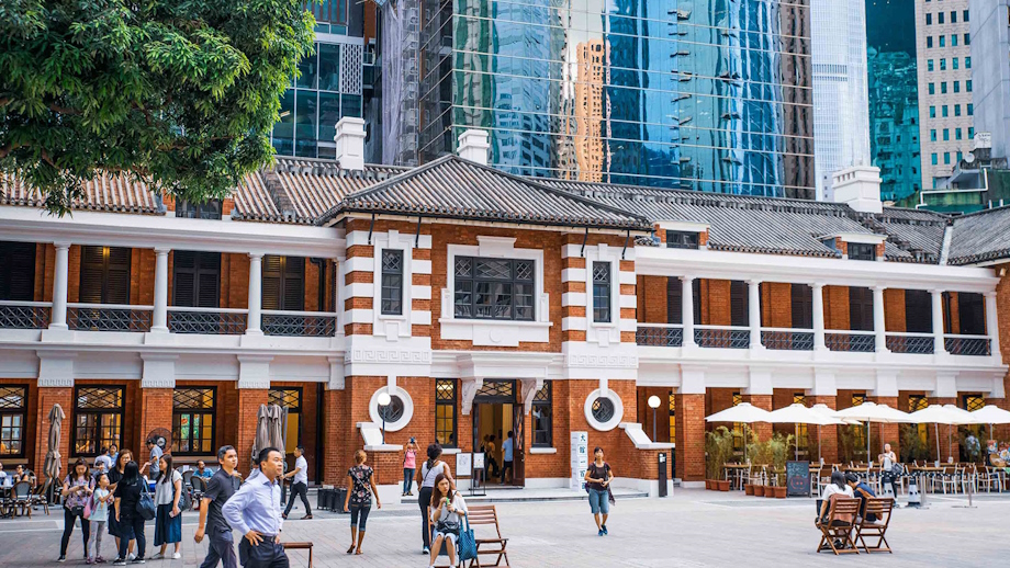 View across the square to the a red brick building that is the former Central Police Station, backed by a partial view of glass skyscrapers