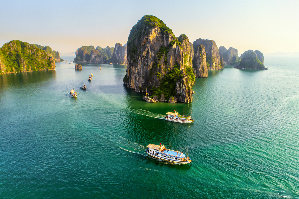 Boats pass in front of some of the limestone karst formations of Halong Bay, Vietnam.